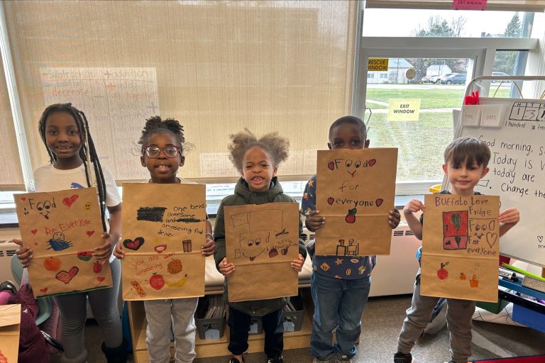 Five students hold large paper bags with colorful drawings and positive messages. The bags will be used to carry food donations.