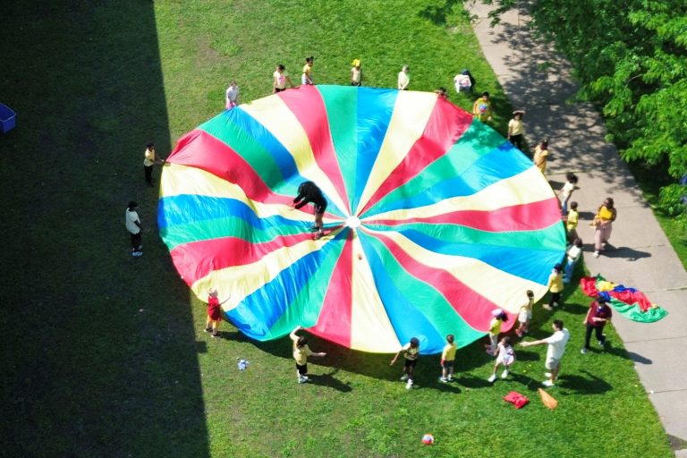 Aerial view of a parachute with students holding it up with one student in the middle of the parachute.